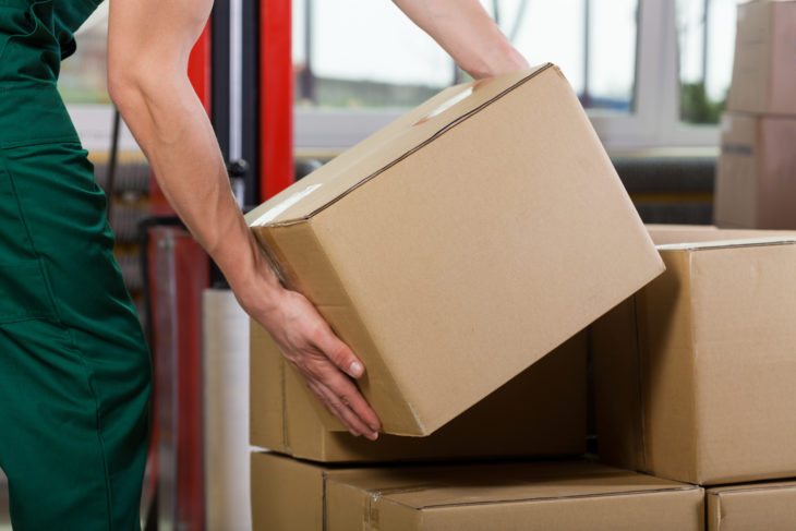 A men lifting a box off another box at work