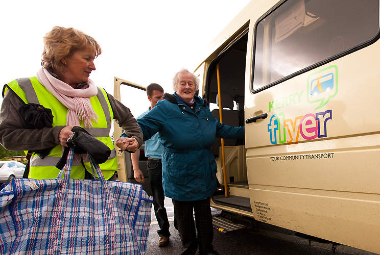 An elder lady getting out the bus, being assisted by a Kerry Flyer career. Caring for elder -Kerry Flyer Transport Services
